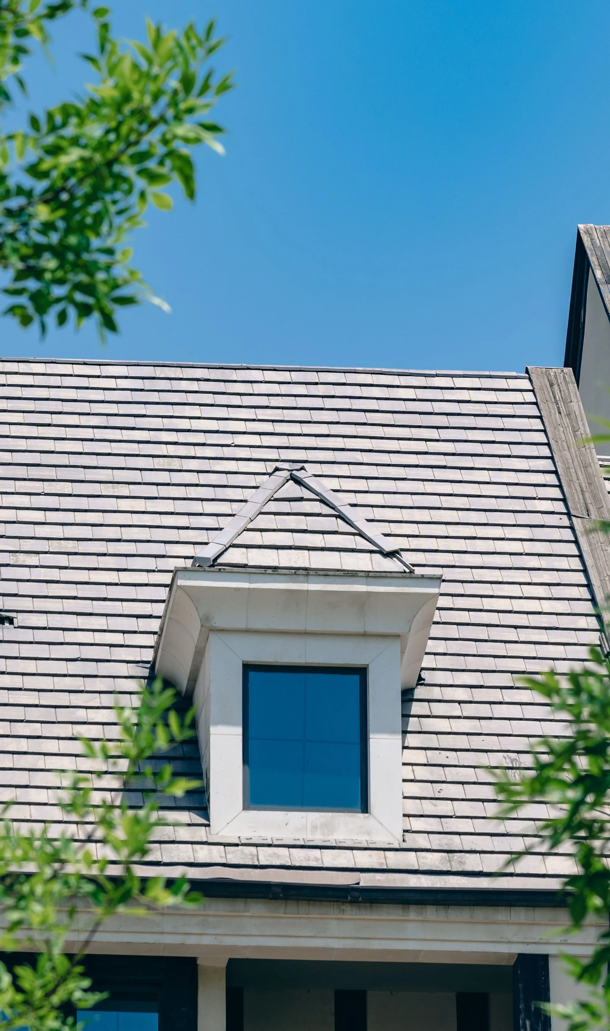 A slate-shingled roof and dormer window on a residential house