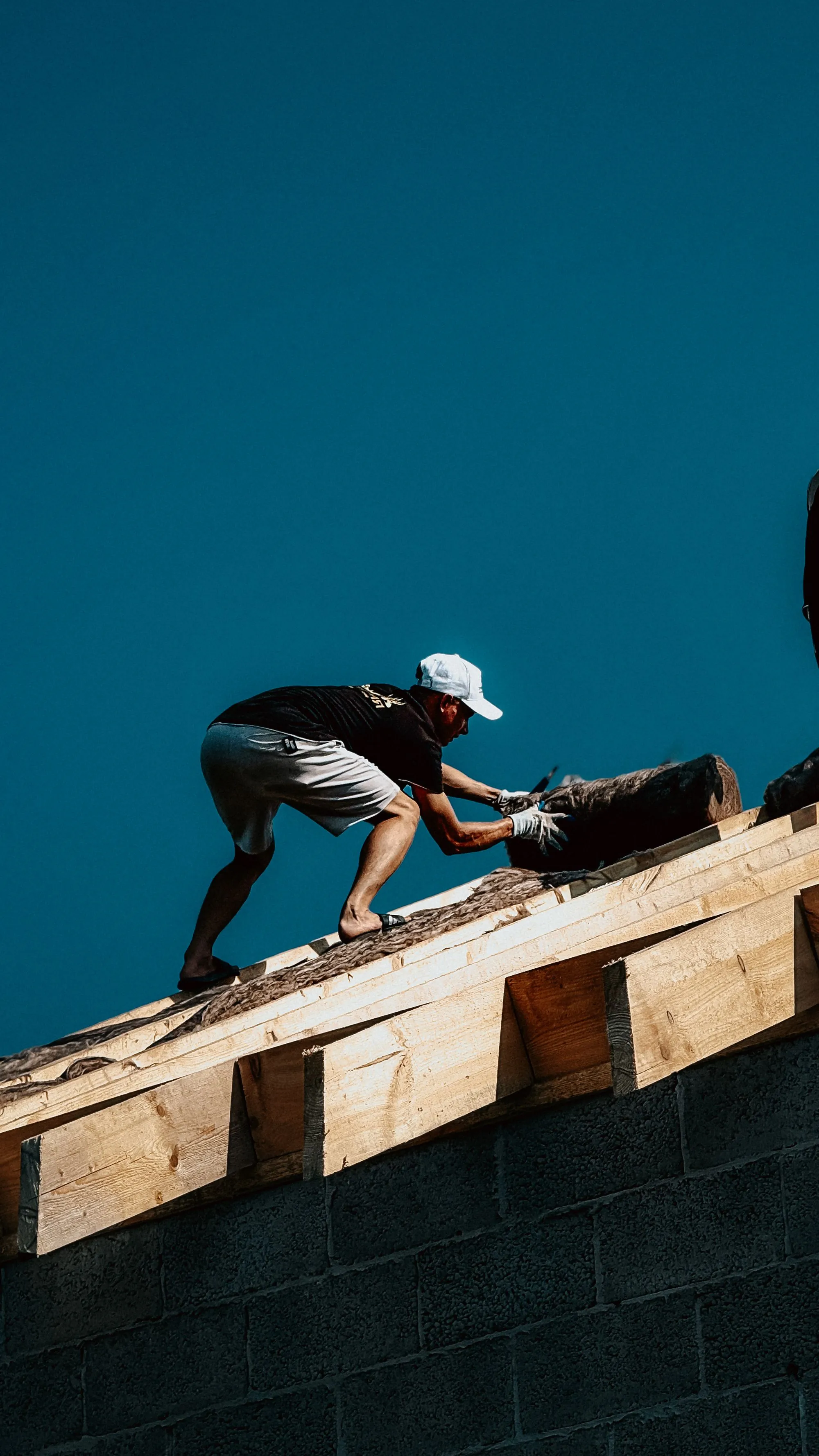 Roofing crew laying new underlayment across a residential roof deck