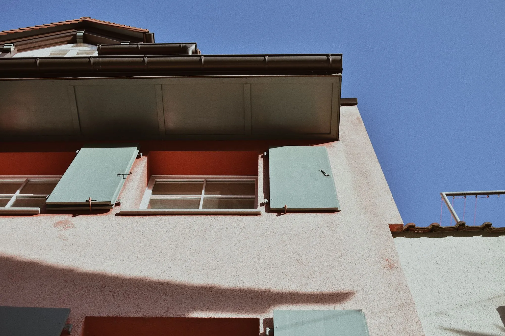 A clean metal gutter and downspout running along the eaves of a house against a blue sky