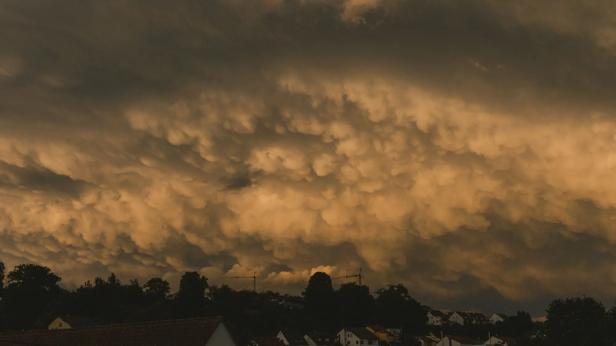 Heavy storm cloud building over a residential skyline at dusk